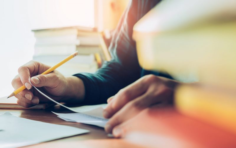 high school,university student study.hands holding pencil writing paper answer sheet.sitting lecture chair taking final exam attending in examination classroom.concept scholarship for education abroad